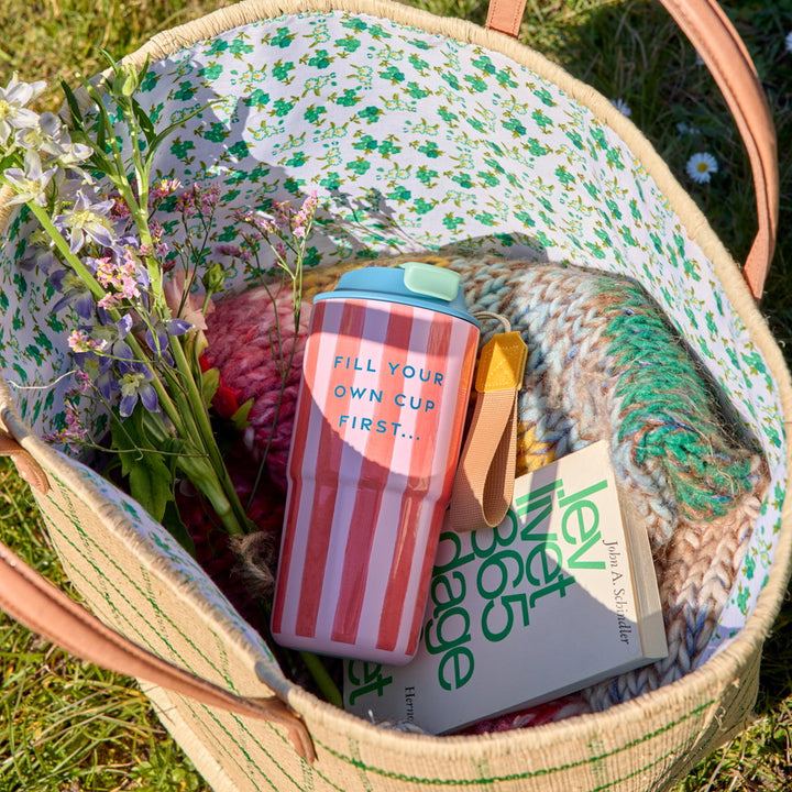 Bild von einem hochwertigen Thermosbecher mit dem Aufdruck" Fill your own cup first" in einem Picknickkorb mit anderen Utensilien für ein gemütliches Picknick